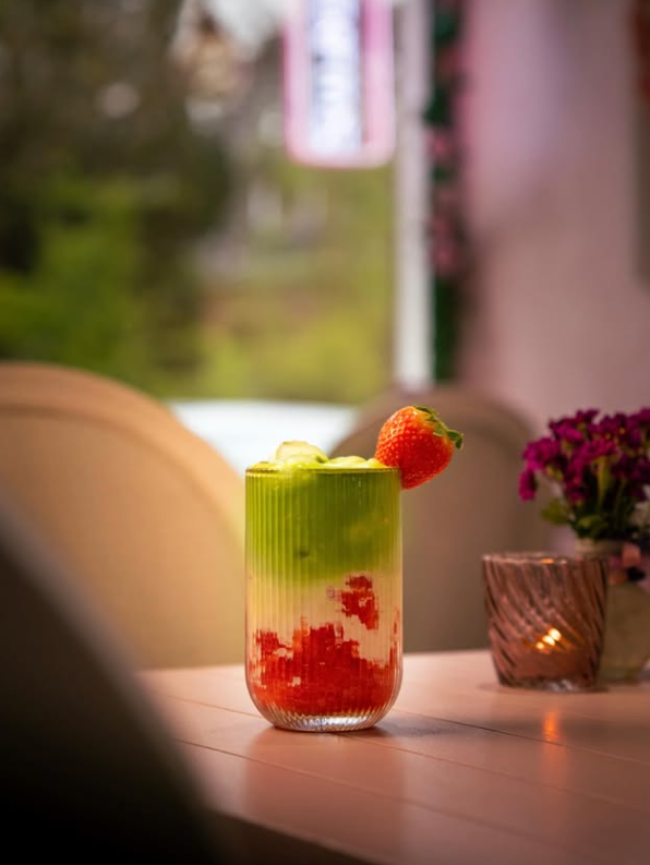 Strawberry Matcha im Rillenglas mit frischer Erdbeere am Fensterplatz